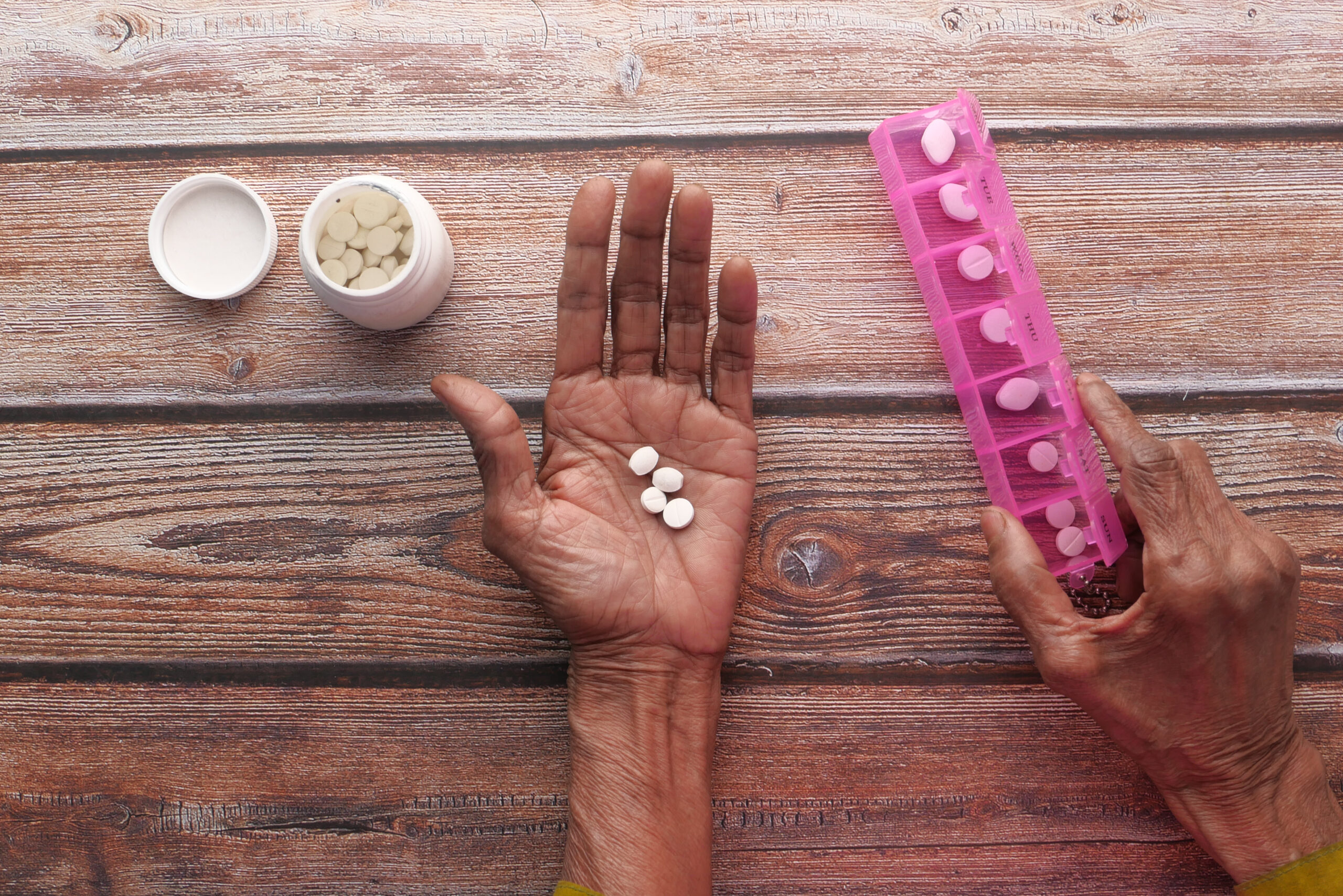 Elderly woman taking medicine from pill box